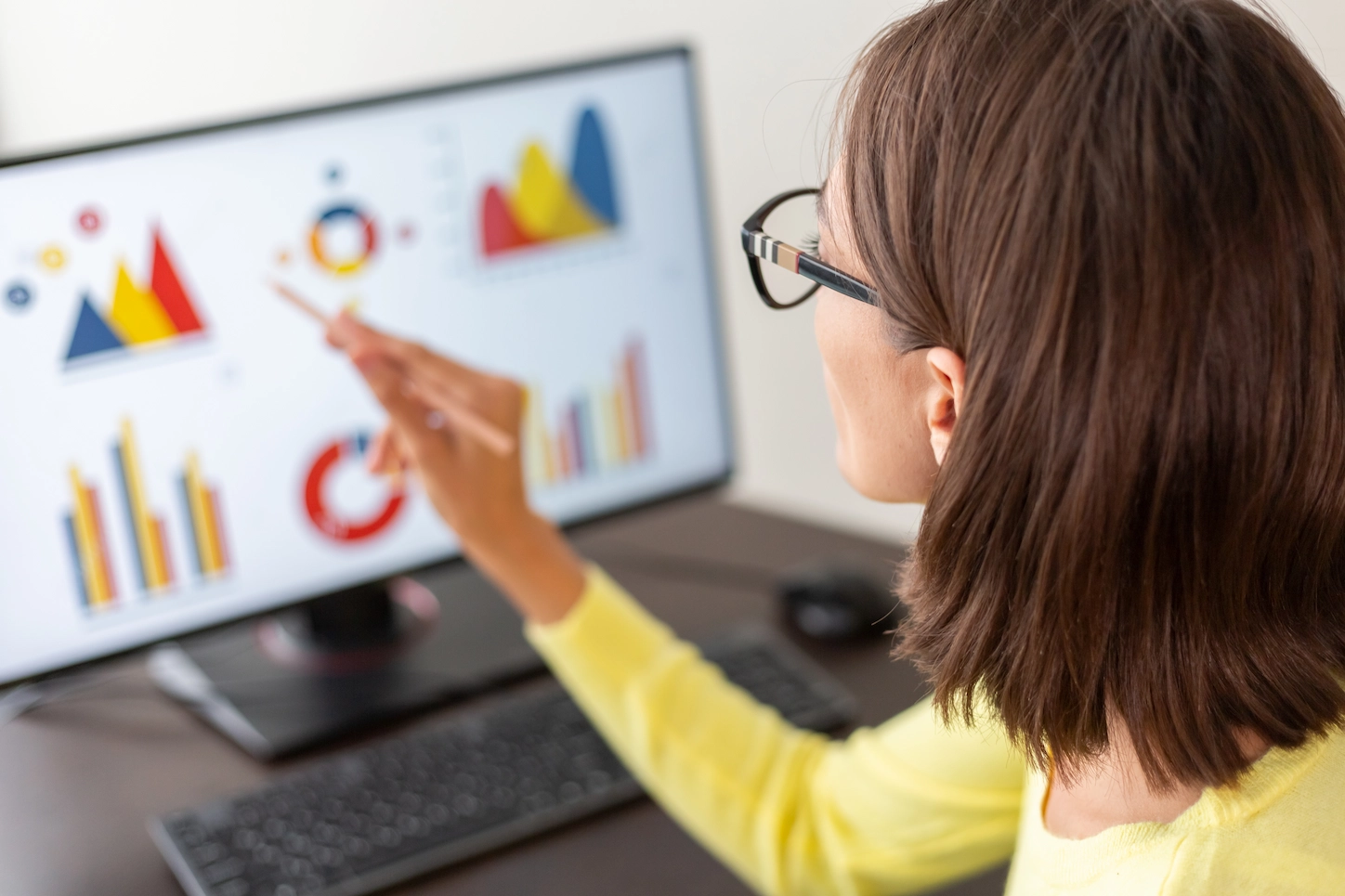 Woman with glasses pointing at dashboards on a screen